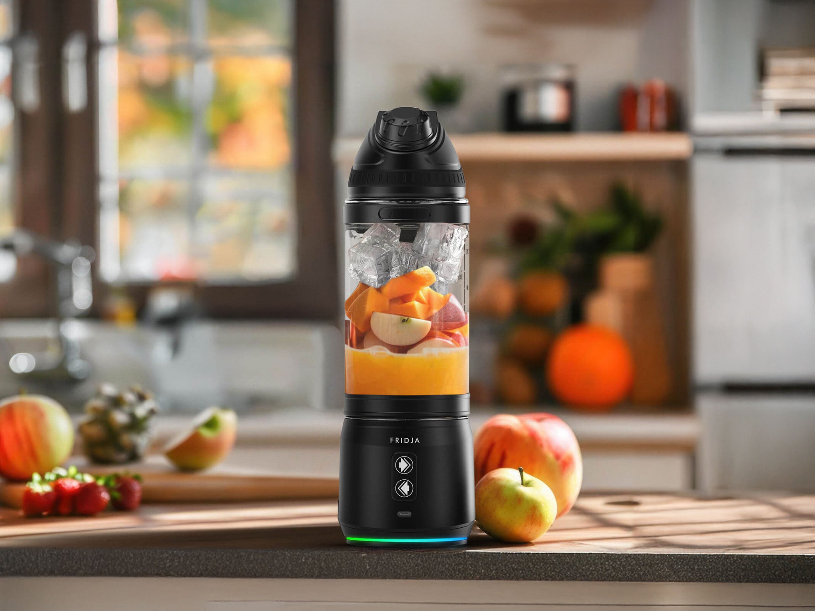 A black portable blender filled with ice, orange juice, and assorted fruit pieces sits on a kitchen counter. Fresh apples and vegetables are nearby, and a window is visible in the background.