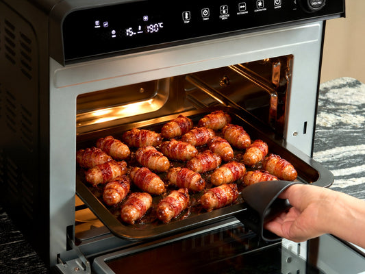 A tray of crispy pigs in blankets being lifted out of the Fridja f77 Super Oven Pro air fryer oven at 190°C