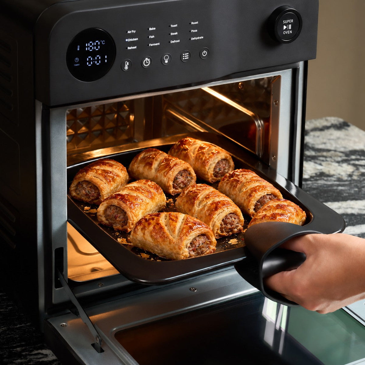 Tray of golden homemade sausage rolls being lifted out of the Fridja f77 Super Oven Pro air fryer oven