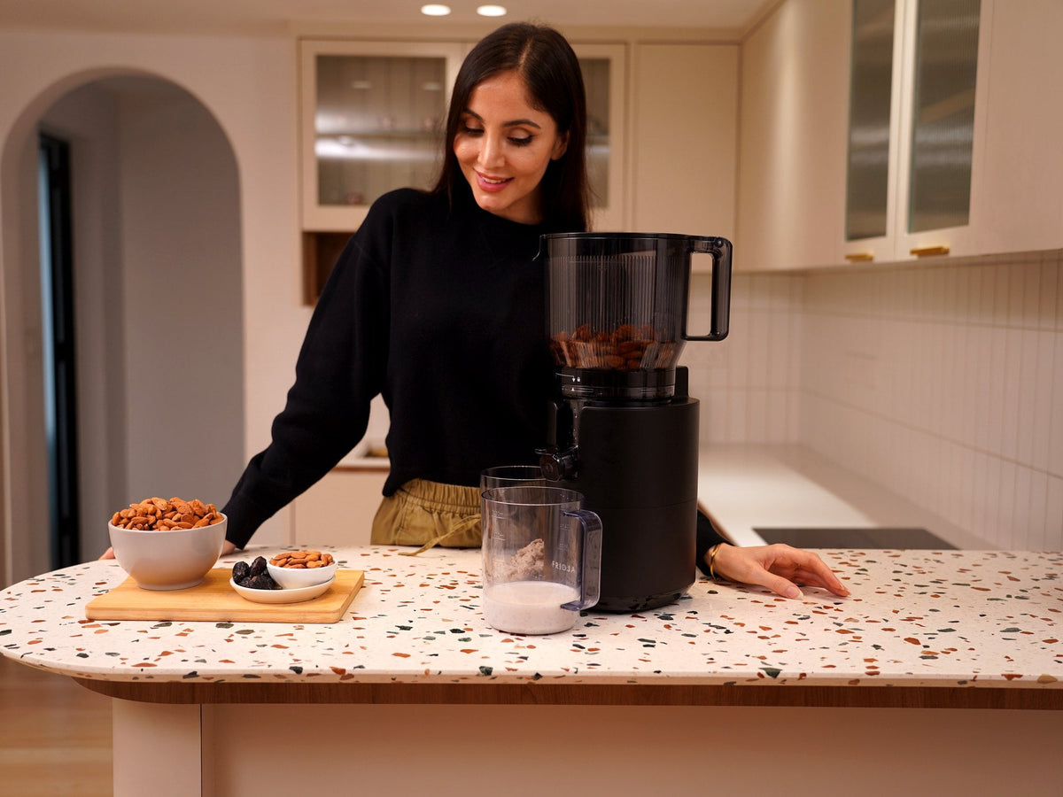Fridja f2800 Open Whole Fruit Juicer on a kitchen worktop with bowls of nuts and seeds ready for homemade milk