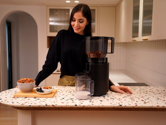 Fridja f2800 Open Whole Fruit Juicer on a kitchen worktop with bowls of nuts and seeds ready for homemade milk