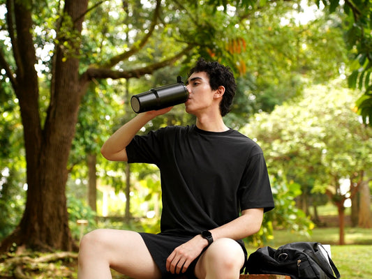 Man drinking a post-workout smoothie from the Fridja f600 Stainless Steel Portable Blender in a park
