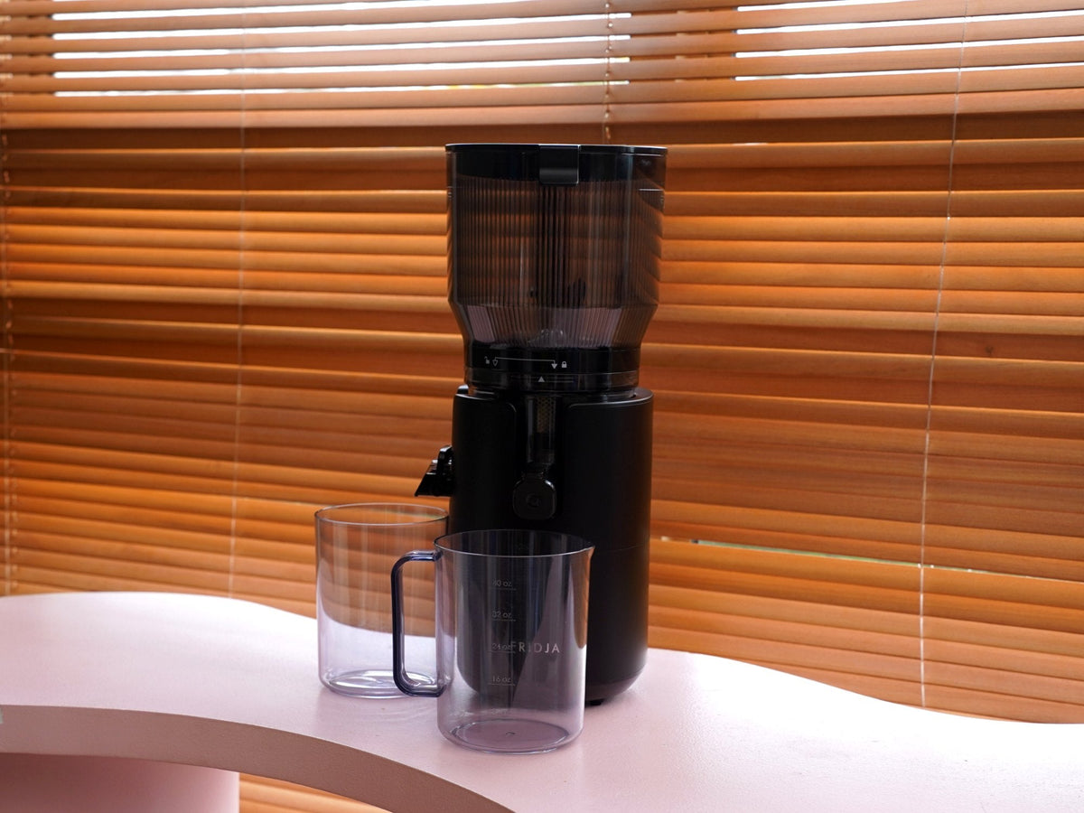 Fridja f2500 Self Feeding Whole Fruit Juicer with its juice and pulp jugs on a kitchen worktop