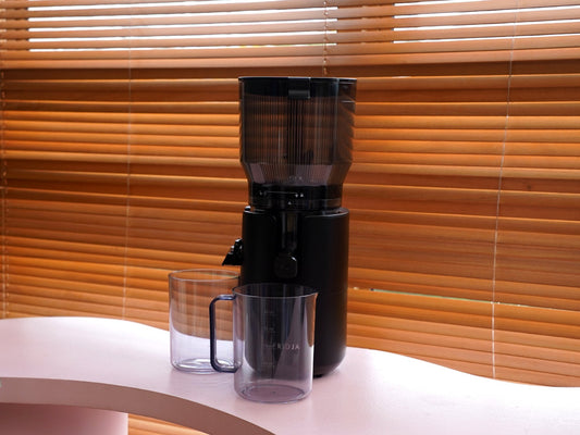 Fridja f2500 Self Feeding Whole Fruit Juicer with its juice and pulp jugs on a kitchen worktop