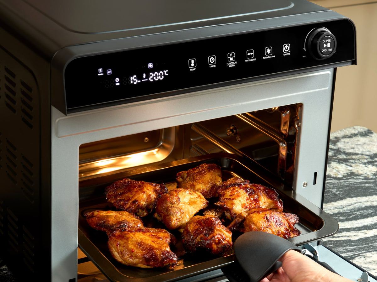Tray of roasted chicken thighs being lifted out of the Fridja f77 Super Oven Pro air fryer oven