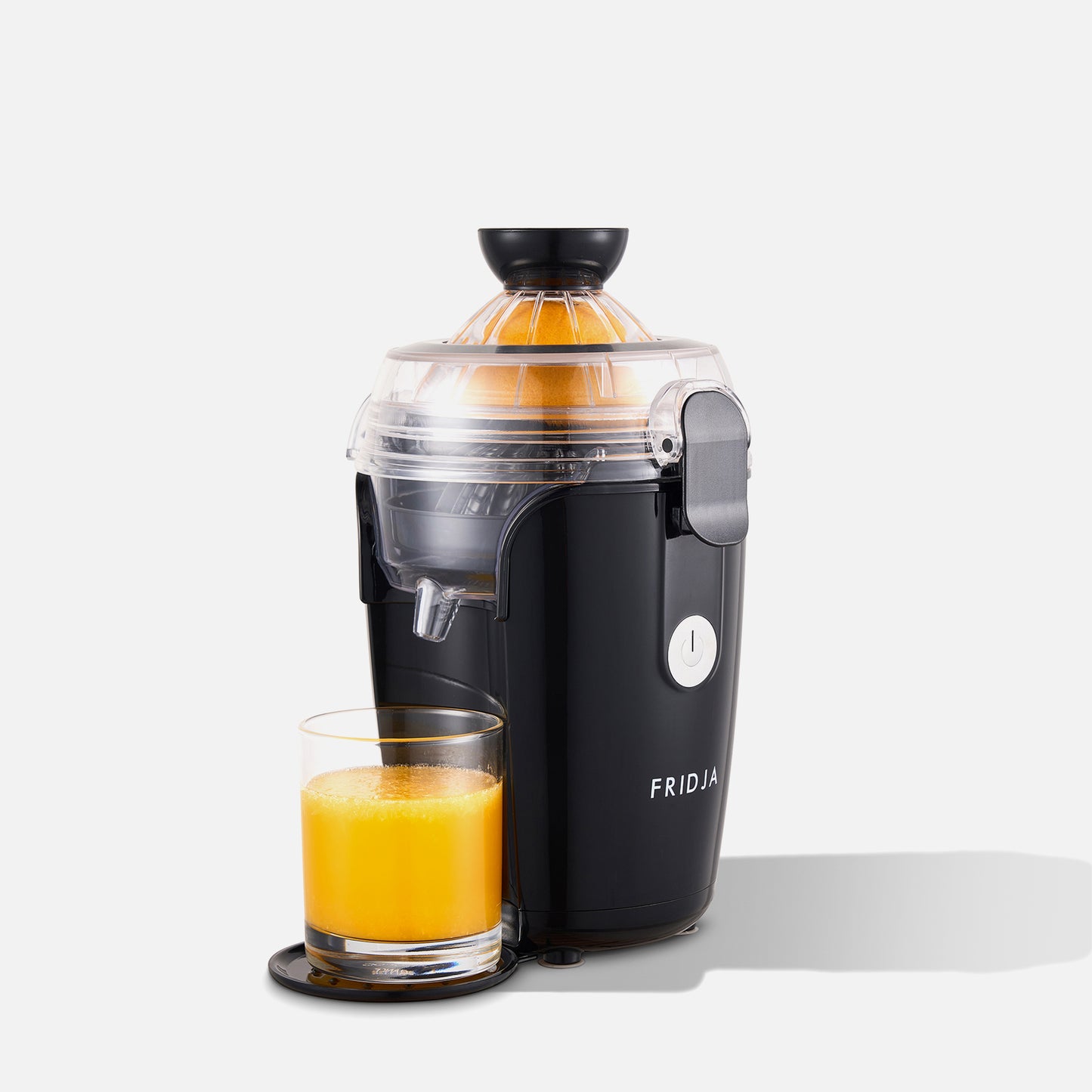 The Fridja Juicer Duo - f800 and f1900, in black, features cold-press technology, a transparent lid, and a white power button. Shown juicing a halved orange into a clear glass of fresh juice.