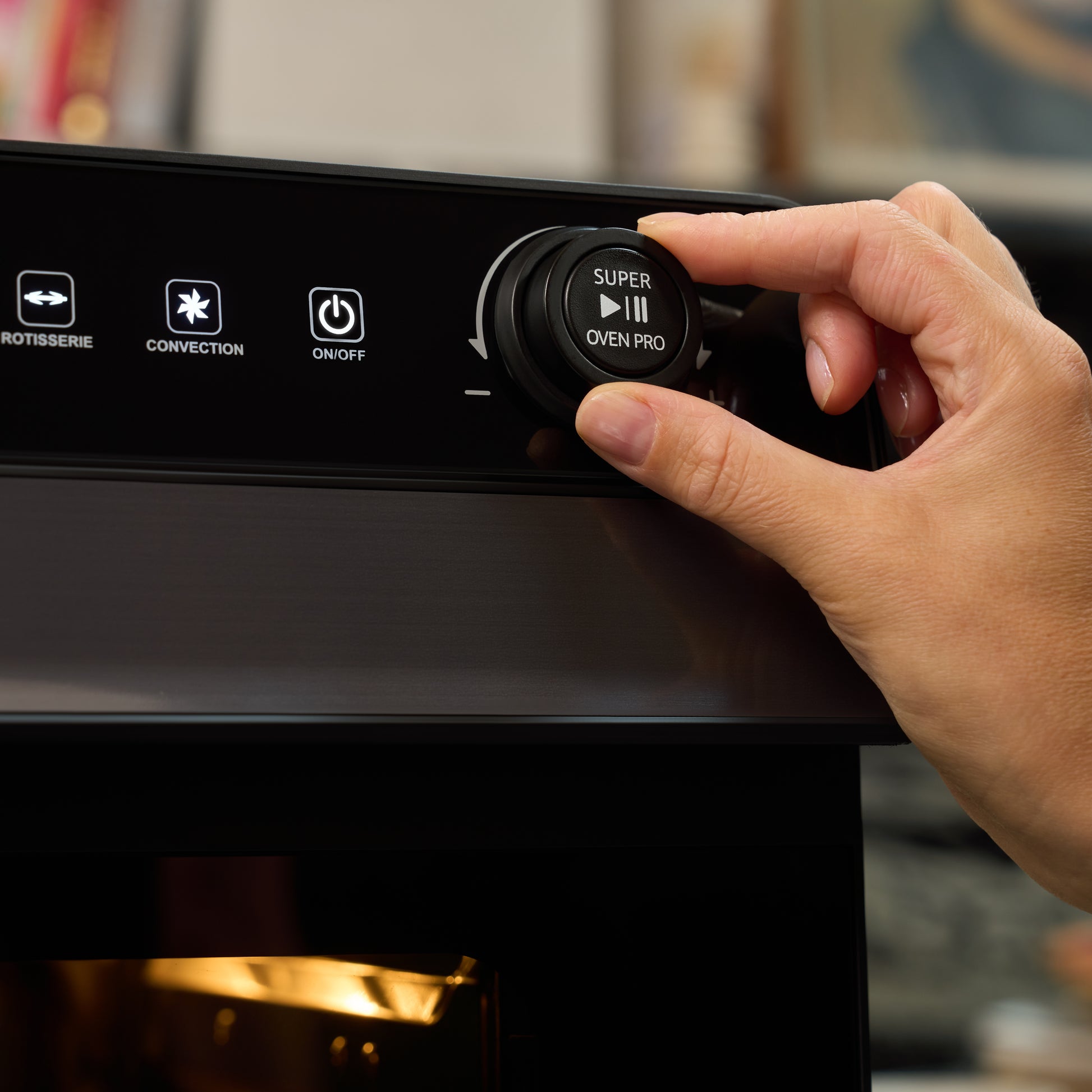 A hand turns the control knob of the Fridja Super Oven Pro - 30L Digital Air Fryer Oven, showing buttons for rotisserie, convection, and on/off on its control panel.