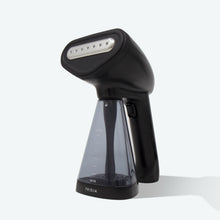 The Fridja f10 Handheld Clothes Steamer, featuring a sleek black design and a transparent water tank, stands upright on a light surface. The Fridja brand name is visible near the base, emphasizing the steamer’s modern aesthetic.