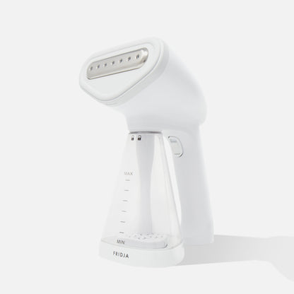 The Fridja f10 Handheld Clothes Steamer is a white device featuring a transparent water tank with clearly marked MIN and MAX levels, and the Fridja brand label at the bottom.