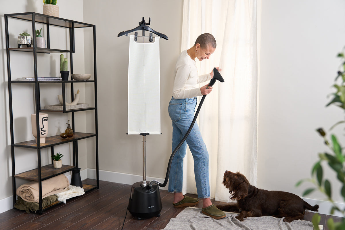 Woman steaming a white shirt at home with the Fridja f1200 Clothes Steamer Pro