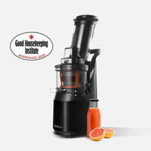 A Fridja f1900 Whole Fruit Juicer in black sits beside a bottle of juice and halved grapefruit, with a Good Housekeeping Institute Approved 2023 badge on the left. Ideal for daily vitamin boosts.