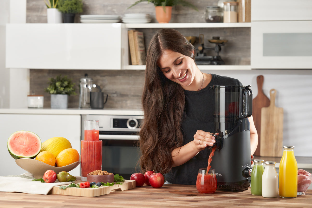 Fresh juice pouring from the anti-drip tap of the Fridja f2500 into a glass