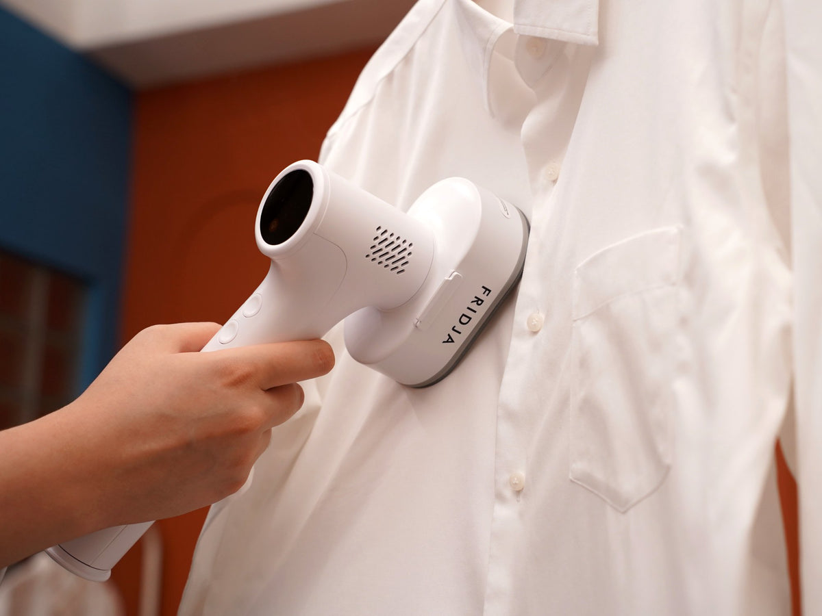 Fridja f20 Handheld Clothes Steamer Pro with Suction smoothing the front of a white shirt on a hanger