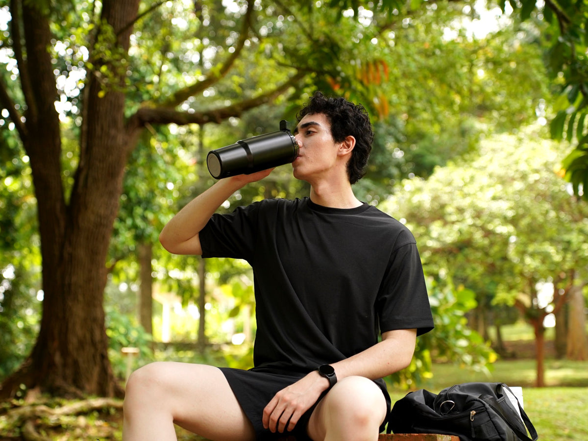 Man drinking a post-workout smoothie from the Fridja f600 Stainless Steel Portable Blender in a park
