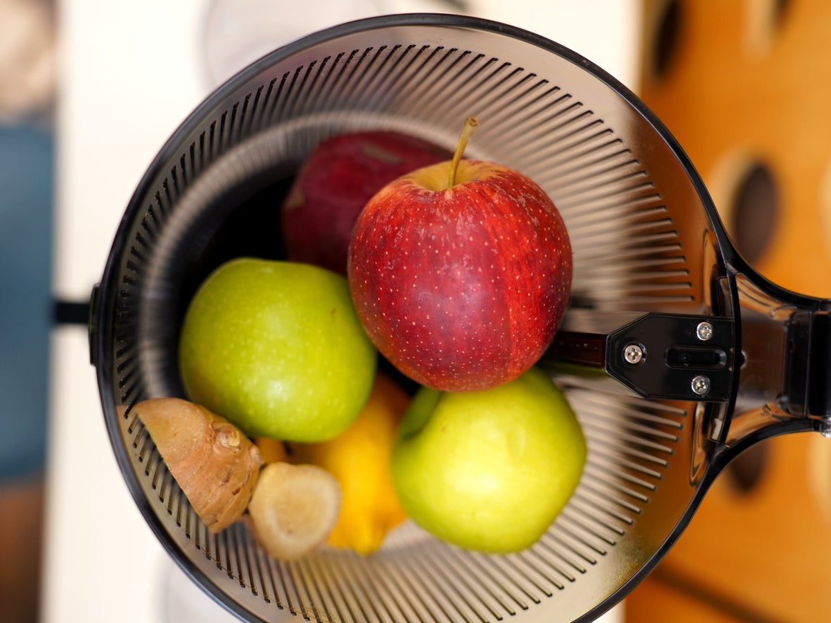 Whole apples, lemon and ginger loaded into the hopper of the Fridja f2500 Self Feeding Whole Fruit Juicer