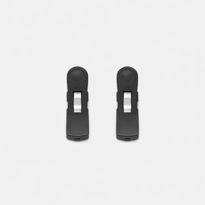 Two identical Fridja f1200 Clips, made of black plastic with silver metal springs, are arranged vertically side by side on a white background as replacement parts for the Clothes Steamer Pro.