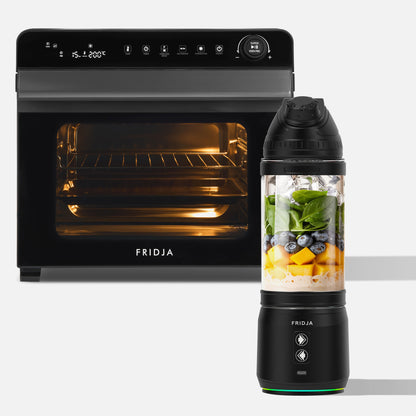 A Fridja Super Kitchen Pro Duo, featuring the f77 Super Oven Pro (open with light on) and the f500 Portable Blender filled with milk, mango, spinach, and blueberries, is displayed against a white background.