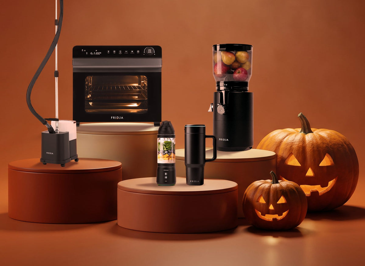 Fridja f2800 Open Juicer, f77 air fryer oven, f1200 steamer, f600 blender and travel mug on podiums with jack-o'-lanterns